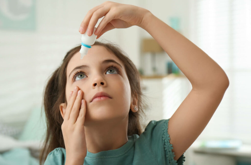 A young girl looking up to put eye drops in her eyes to relieve the irritation of dry eye