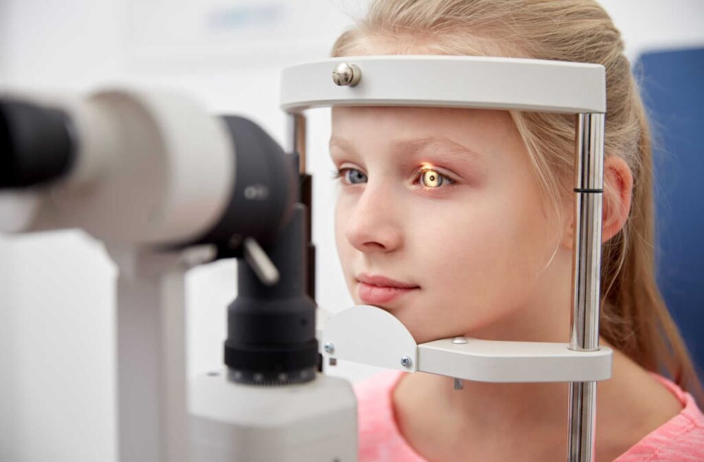 A young girl having her eyes assessed with a slit lamp during a routine eye exam