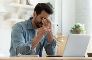 Young man suffering from eye strain after spending some time using his laptop