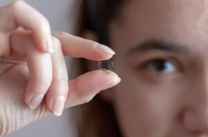 Woman holding a single Ortho-k lens between her fingers