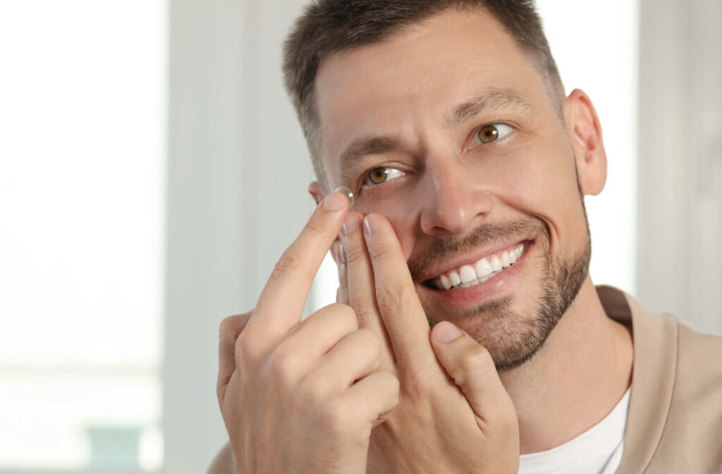 A man putting a contact lens in his right eye using his right hand with his left hand holding his eyelid